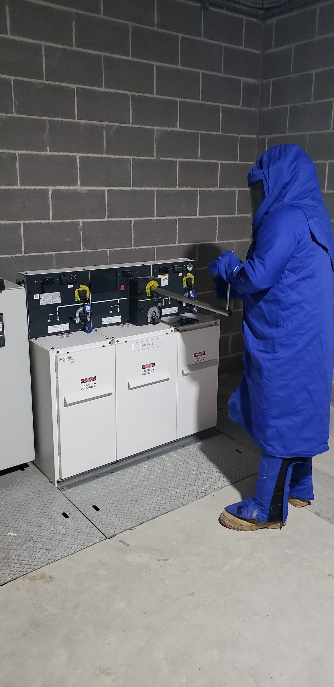 An electrician in full arc flash protection operating a switchboard