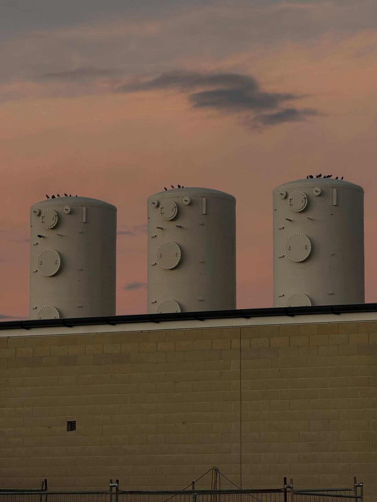 Process tanks silhouetted against a dusk sky at a utility site