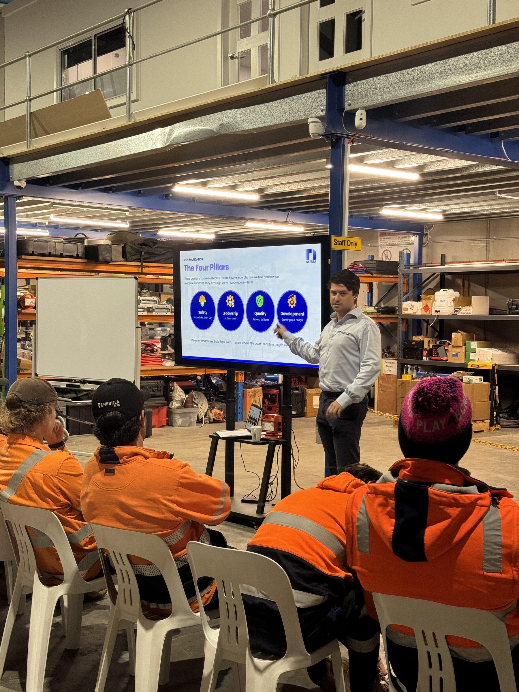 A classroom session in the workshop, the crew seated in front of a screen